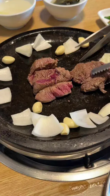 잘 구워진 한우를 집게로 들어올리는 모습