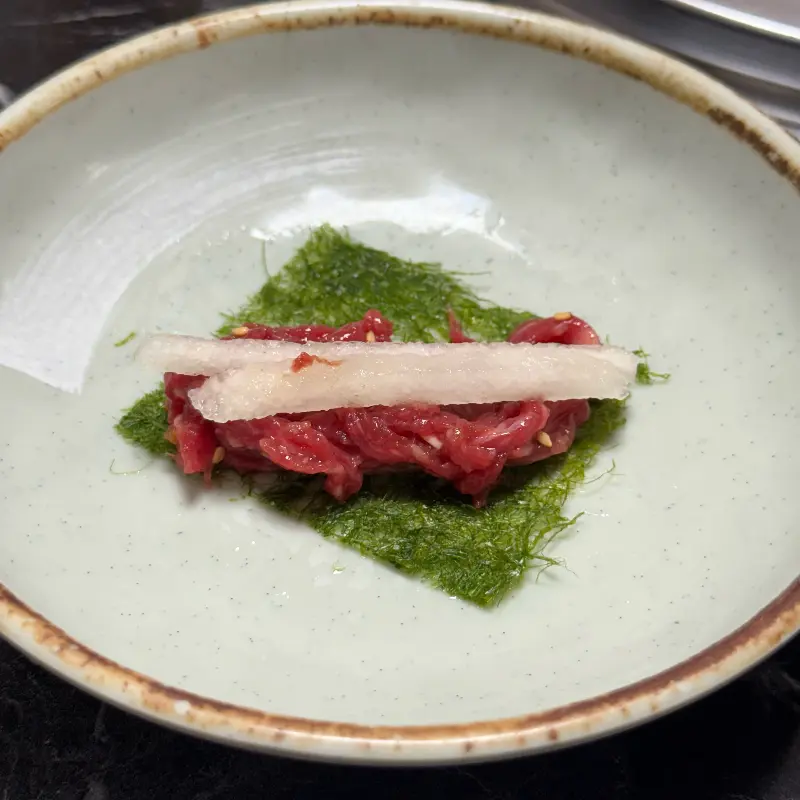 감태 위에 육회 한 점과 무채를 올린 모습