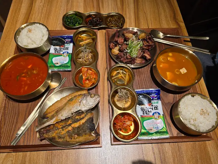 두 개의 나무 쟁반 위에 각각 밥, 국, 반찬, 메인 요리가 정갈하게 차려져 있습니다.