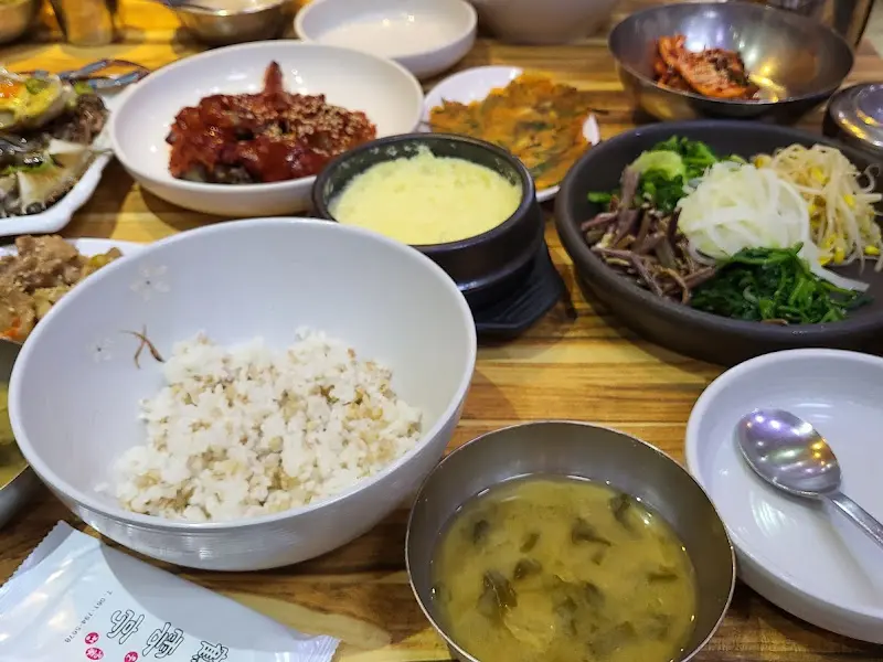 다채로운 밑반찬과 간장게장, 양념게장, 그리고 비빔밥이 차려진 테이블 전경