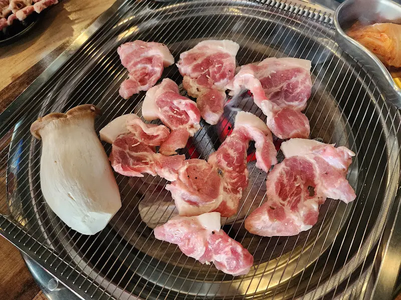 숯불 위에서 꼬들목살이 맛있게 익어가는 모습