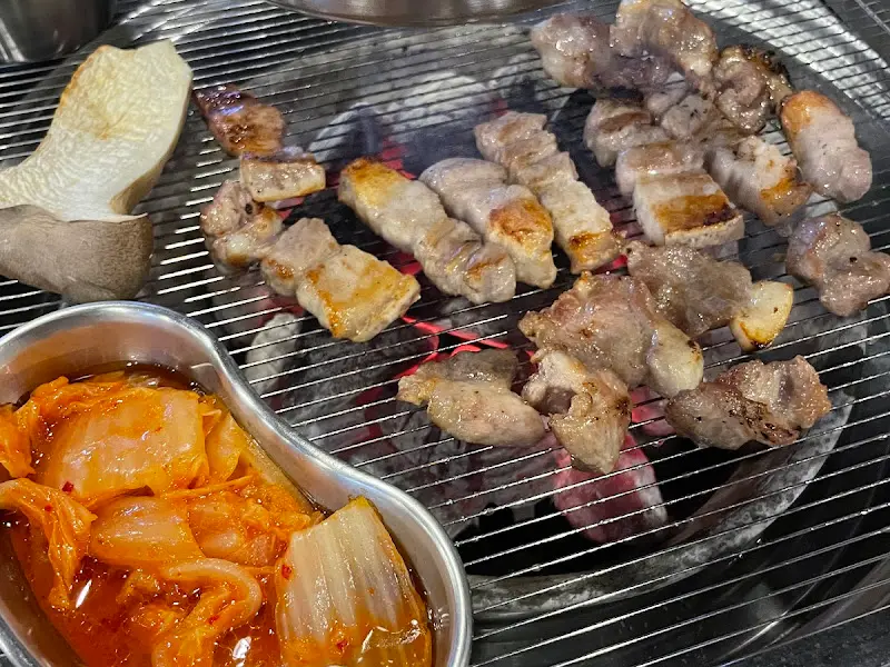 불판 위에서 꼬들목살과 김치가 함께 구워지는 모습