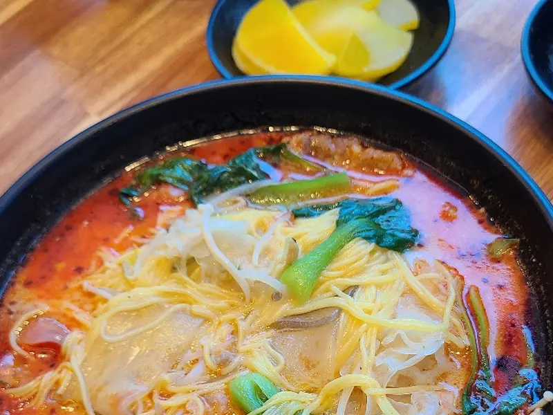 노란 면과 녹색 채소가 어우러진 마라탕의 클로즈업 샷