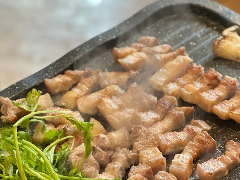 불판 위에서 지글거리는 삼겹살과 미나리