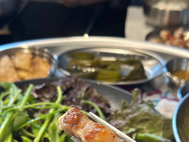 잘 구워진 삼겹살을 젓가락으로 집는 모습