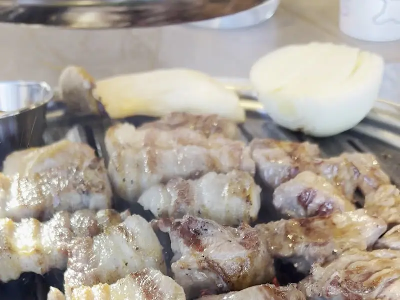 불판 위에서 익어가는 삼겹살과 버섯, 양파