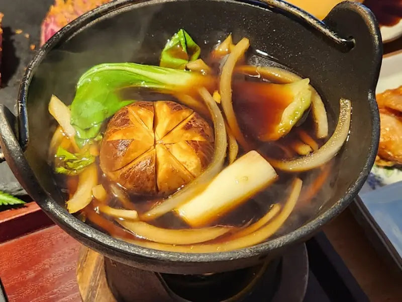 스키야키 냄비 안에서 야채와 함께 끓고 있는 우동 면발