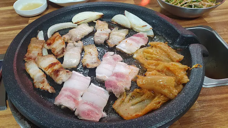 불판 위에서 익어가는 삼겹살과 김치