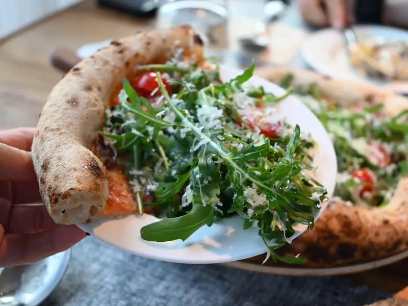 루꼴라 피자를 들어 올리는 모습