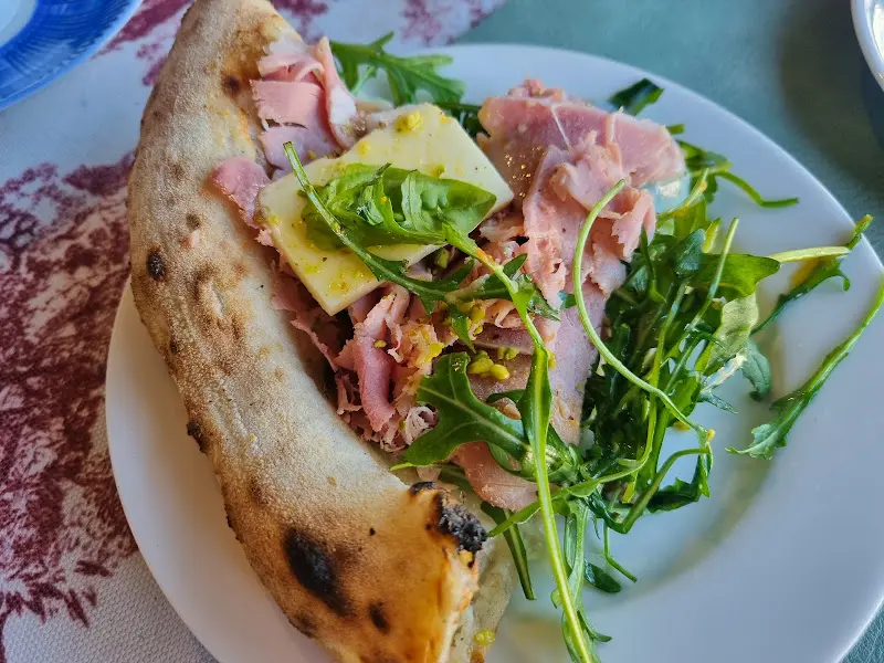 신선한 루꼴라와 햄이 조화로운 피자 한 조각