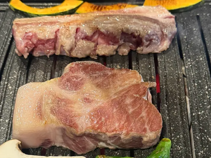 잘 달궈진 불판 위에 올라간 두툼한 흑돼지 목살과 삼겹살