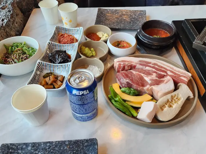 준비된 흑돼지, 멜젓, 김치찌개, 곁들임 찬, 음료수 등이 테이블에 푸짐하게 차려져 있어요