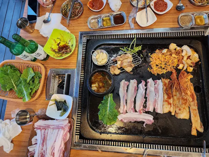 푸짐하게 차려진 삼겹살과 반찬, 소주병들이 놓인 테이블 모습