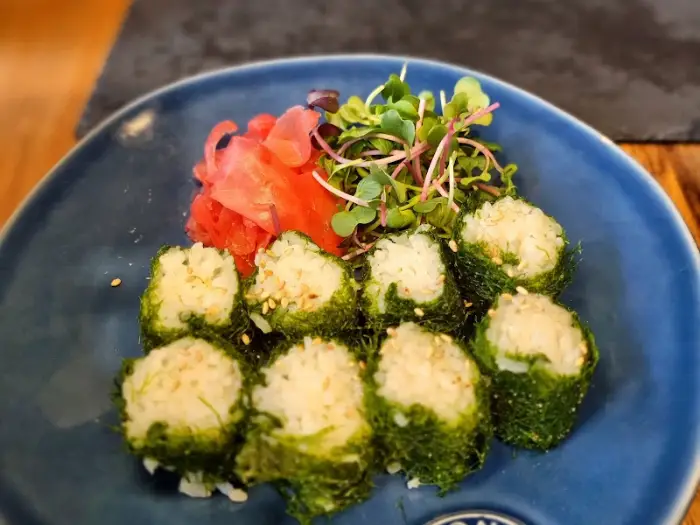 동그랗게 말린 감태초밥과 곁들임 샐러드. 신선한 채소와 함께 플레이팅되어 있다.