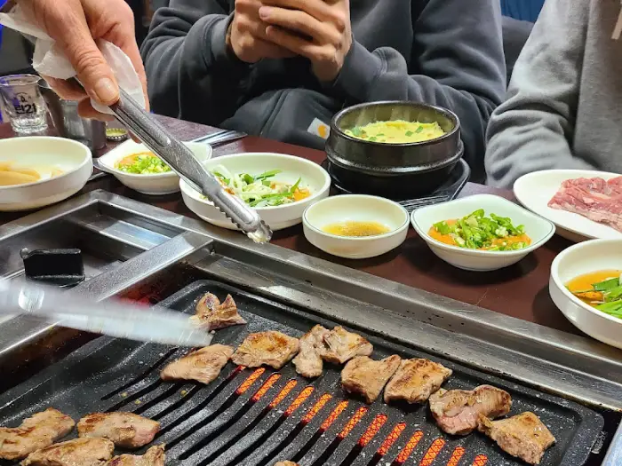 굽고 있는 고기를 집게로 옮기는 손