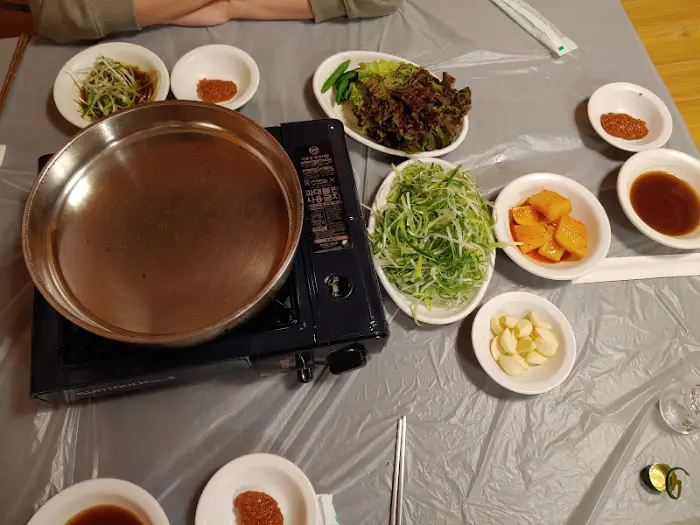 식탁에 차려진 등심, 불판, 곁들임 반찬 등의 전체 모습