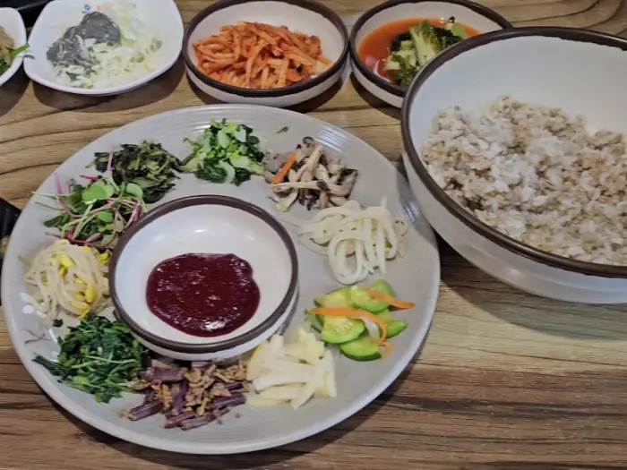 다양한 나물과 쌈 채소, 그리고 고추장이 담긴 비빔밥 준비용 접시