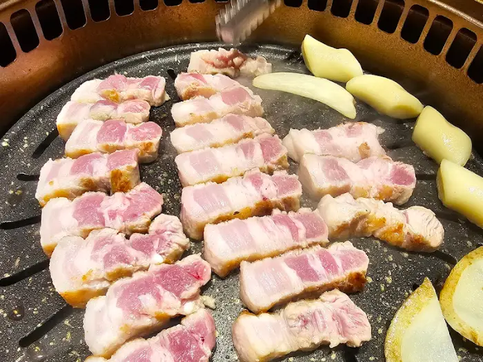 불판 위에서 익어가는 두툼한 삼겹살 덩어리들