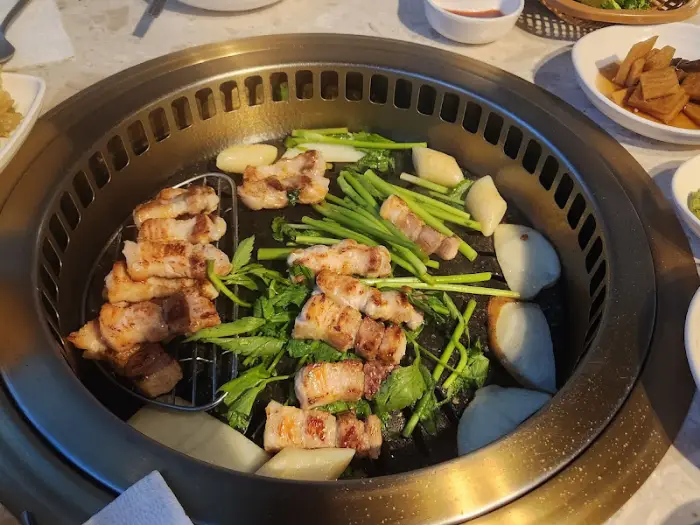 고기, 미나리, 감자 등이 불판 위에서 함께 구워지고 있는 모습