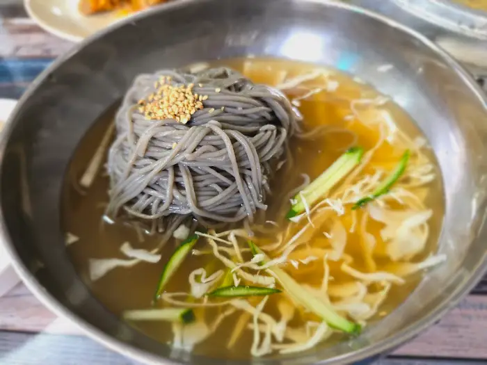 시원한 육수에 메밀면과 오이가 담겨 있는 물 막국수