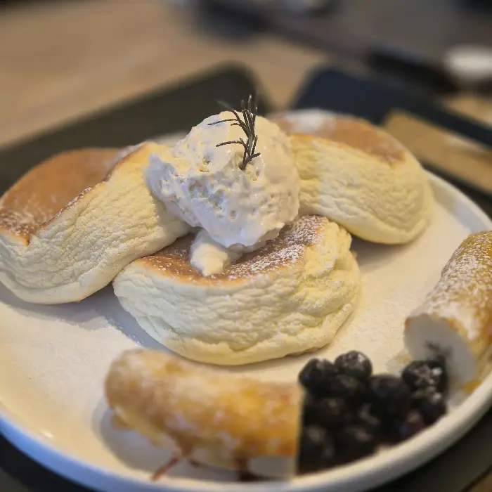 크림과 과일이 곁들여진 젠젠 수플레 팬케이크. 로즈마리 장식이 특징이다.