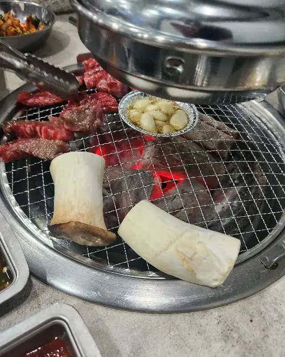 숯불 위에서 익어가는 소갈비살과 곁들임 버섯, 마늘