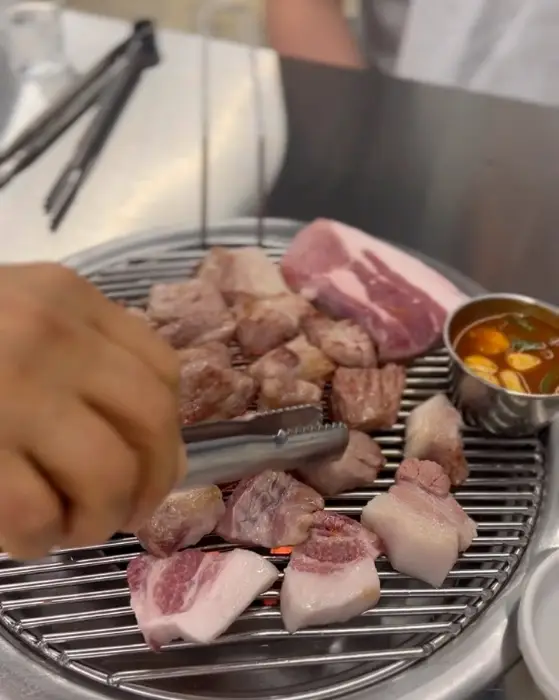 가위와 집게를 이용해 흑돼지 고기를 굽고 있는 모습