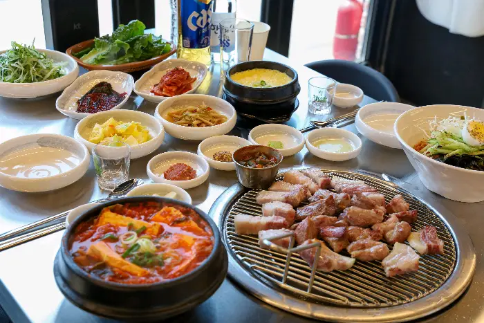 다양한 밑반찬과 김치찌개, 그리고 흑돼지 구이가 차려진 식탁