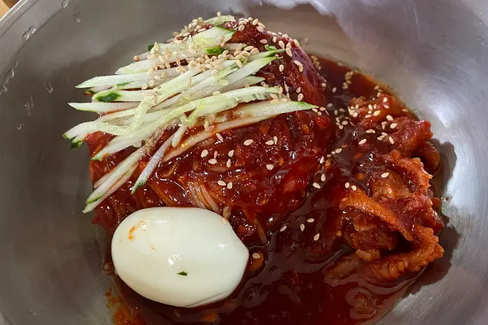 먹음직스러운 비빔밀면의 모습. 붉은 양념과 신선한 채소가 어우러져 식욕을 자극합니다.