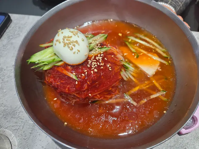 그릇에 담긴 물밀면. 맑은 육수와 고명들이 어우러져 시원한 느낌을 줍니다.