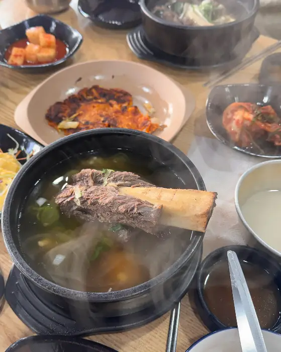 테이블에 놓인 여러 음식들, 왕갈비탕과 부침개, 김치 등