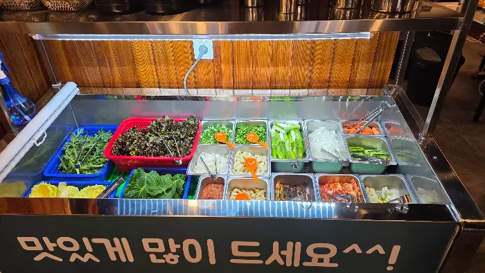 다양한 종류의 신선한 채소와 곁들임 반찬들이 가지런히 놓여있는 셀프바