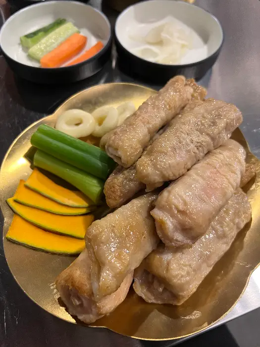 접시에 담긴 쫄깃한 막창과 곁들임 채소, 그리고 떡