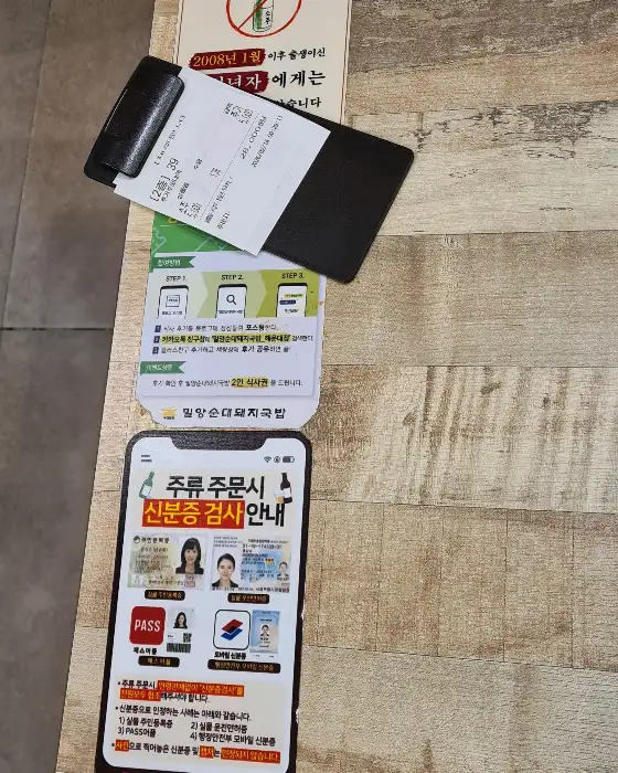 테이블 위에 놓인 결제 영수증과 신분증 검사 안내 문구