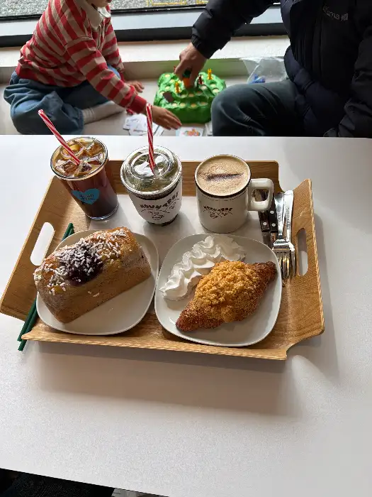 트레이에 담긴 커피, 빵, 휘핑크림과 아이가 놀고 있는 모습