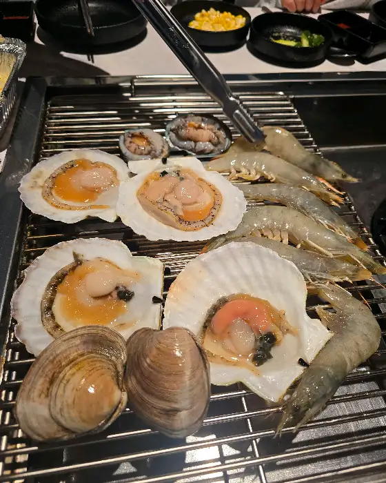 팬 위에 구워지고 있는 조개와 새우, 관자 등 다양한 해산물