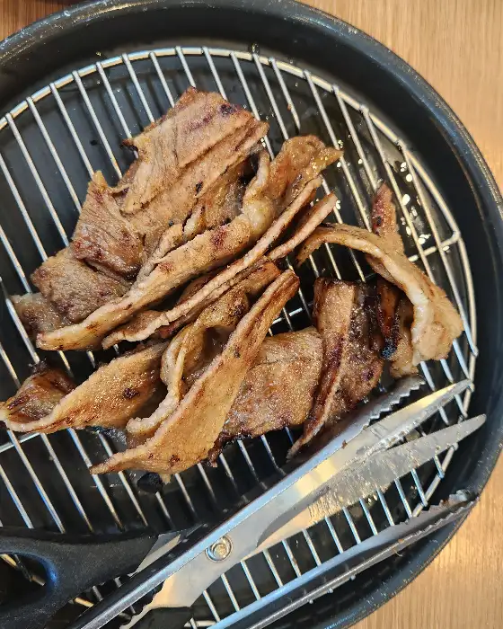 철망 위에 놓인 숯불고기의 근접 사진. 숯불 자국이 선명하게 보인다.