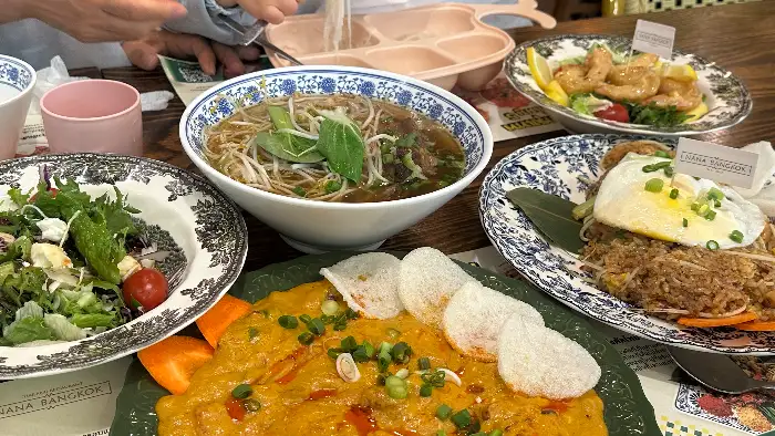 여러 태국 요리가 테이블에 차려진 모습. 쌀국수, 볶음밥, 샐러드, 꿍팟퐁커리가 보인다.