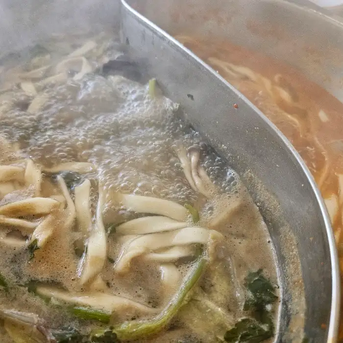 끓고 있는 샤브샤브 냄비에 넙적한 수제비가 들어가 있는 모습