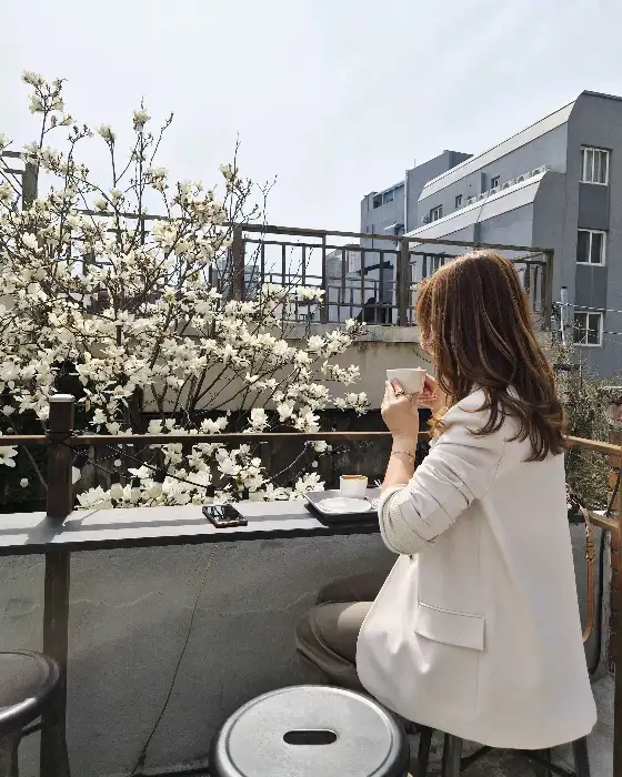 목련꽃을 배경으로 커피를 마시는 여성
