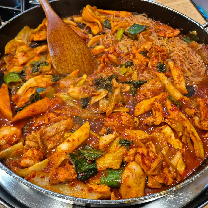 먹음직스럽게 볶아진 닭갈비와 쫄면 사리, 채소의 모습