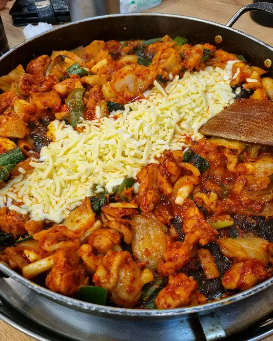 김이 올라오는 닭갈비 철판에 치즈가 녹아내리는 모습