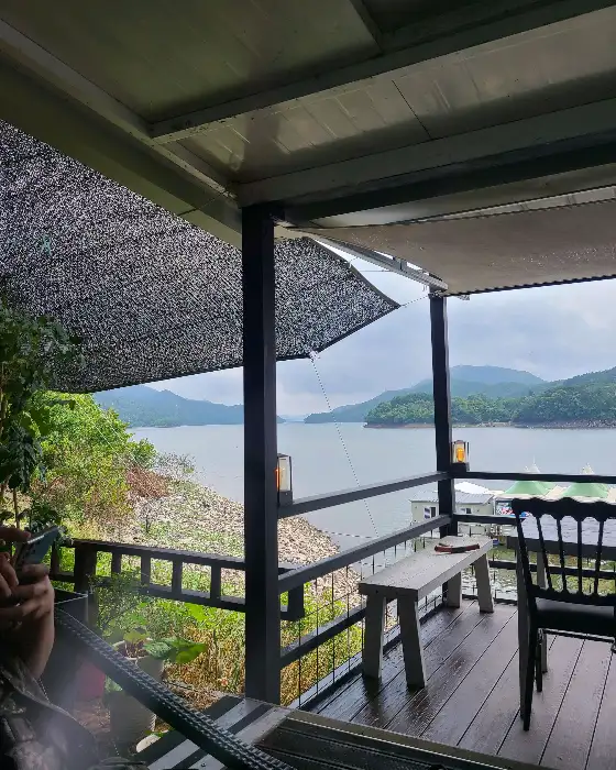테라스 좌석에서 바라보는 장성호의 풍경과 숲이 우거진 산들이 보인다.