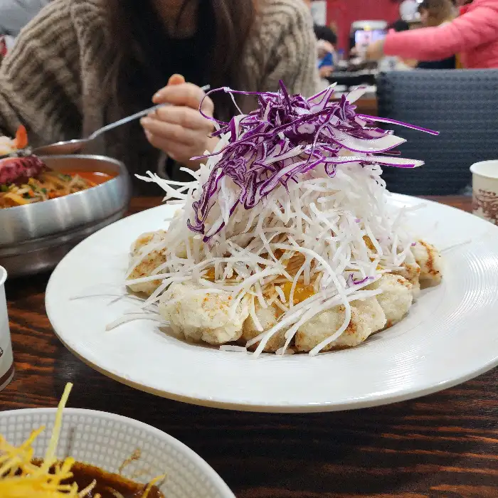 수북이 쌓인 채 썬 순무 위에 탕수육이 얹어져 있는 모습