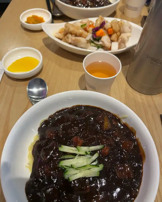 짜장면 위에 얇게 채 썬 오이가 보기 좋게 올라가 있습니다.