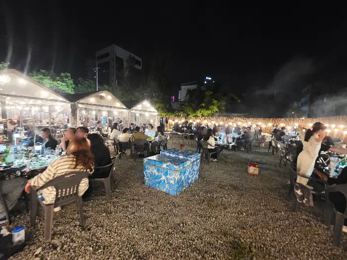 야외 테이블에 사람들이 모여 앉아 즐거운 시간을 보내는 모습