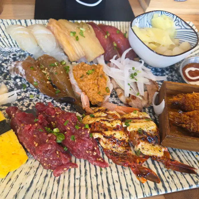 초밥과 튀김, 샐러드 등이 푸짐하게 담겨 있는 접시