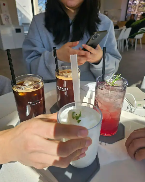 테이블 위에 놓인 다양한 음료와 한 사람이 스마트폰을 보고 있는 모습