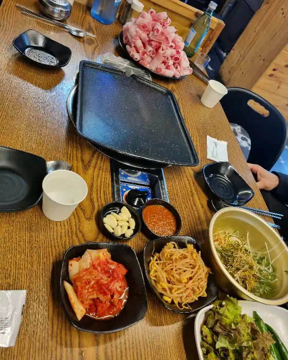 테이블 위에 차려진 다양한 반찬과 대패삼겹살