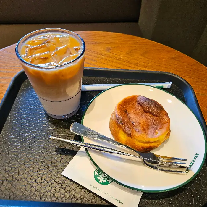 테이블 위에 놓인 아이스 라떼와 둥근 빵